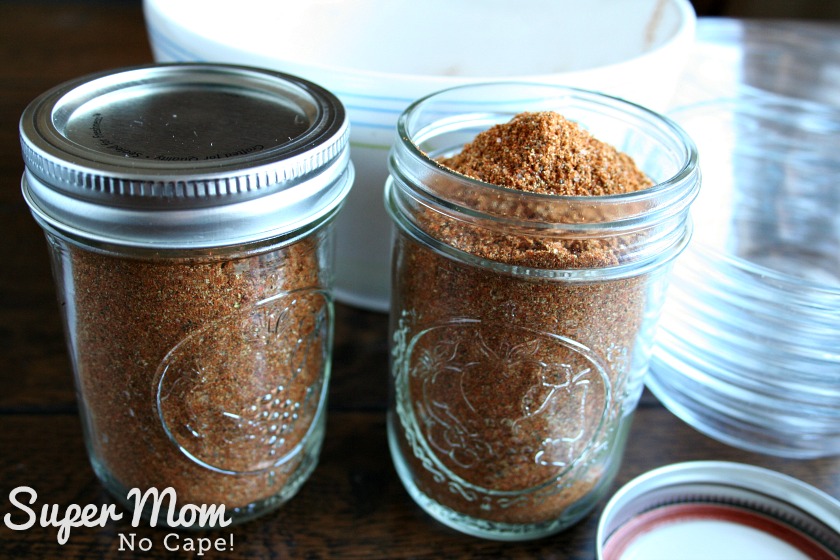 Two half pint jars filled with Homemade Taco Seasoning with a white bowl and several small glass bowls in the background