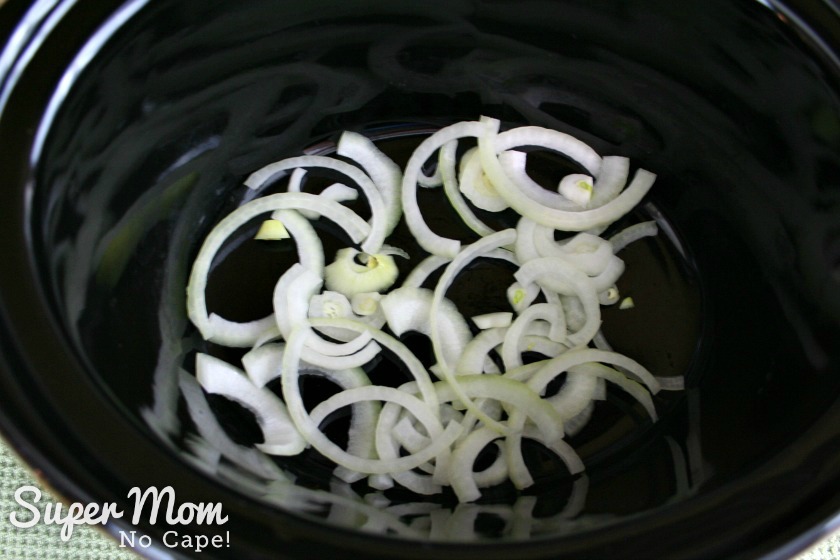 Layer of sliced onions added to the bottom of the slow cooker