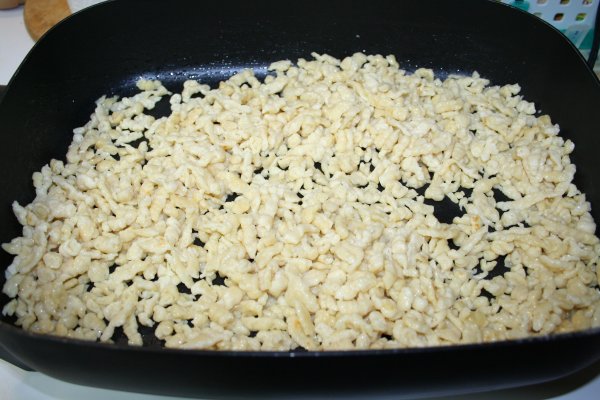 Homemade spaetzle being fried in an electric frying pan