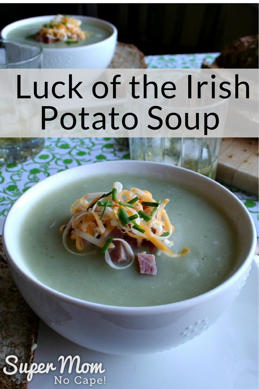 Two bowls of Luck of the Irish Potato Soup and a cutting board with a loaf of bread
