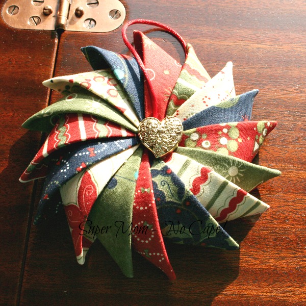A gold heart shaped button sewn to the center of the Prairie Point Star Ornament