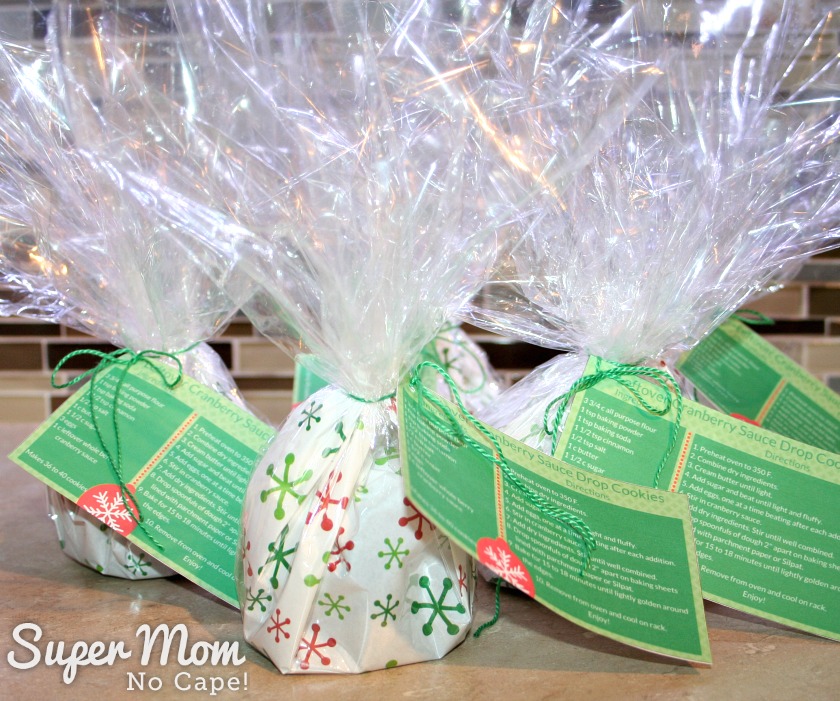 Five cookie exchange packages with the cookies inside cellophane wrapping and recipe cards attacked.