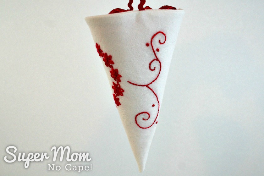 Side view of the white fabric cone showing the red embroidered swirls with off white background