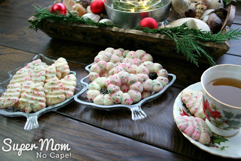 Christmas Lights Shortbread Cookies - Tray of Tree shaped cookies and tray of wreath shaped cookies with cup of tea