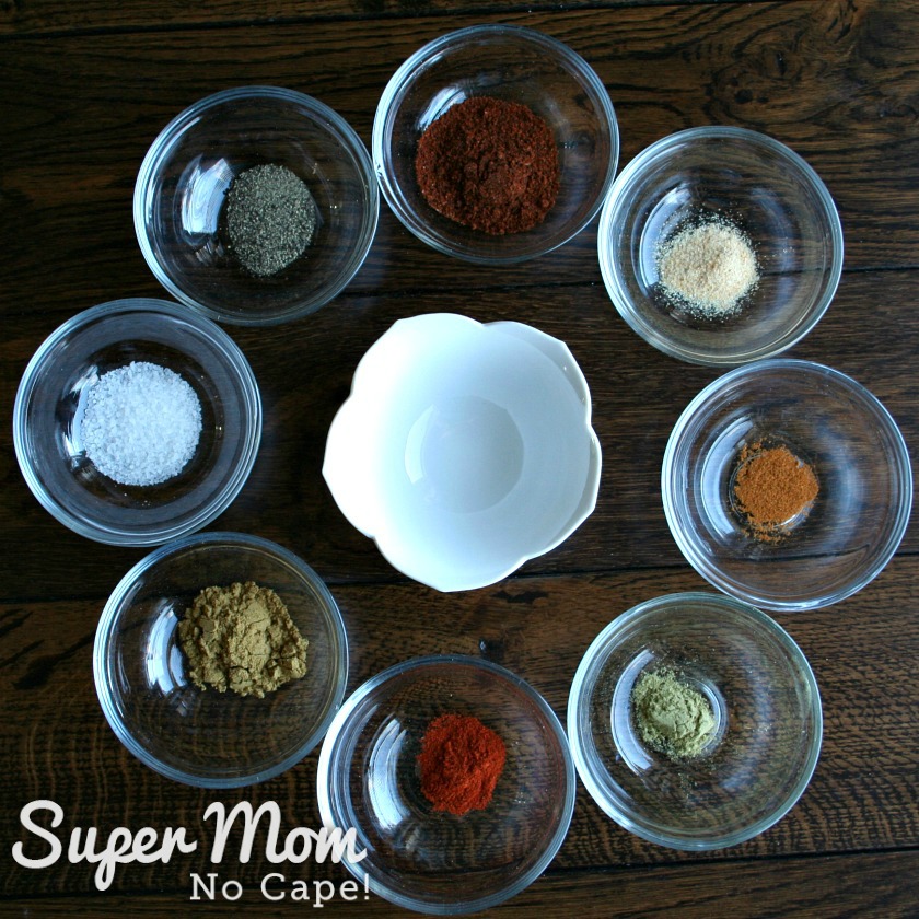 8 small glass bowls with measured ingredients for homemade Taco Seasoning surrounding an empty small white bowl