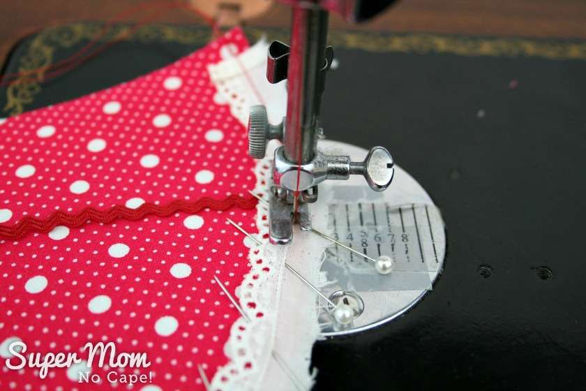 Photo of the white eyelet trim being machine basted in place on the red with white polka dot fabric cone piece.