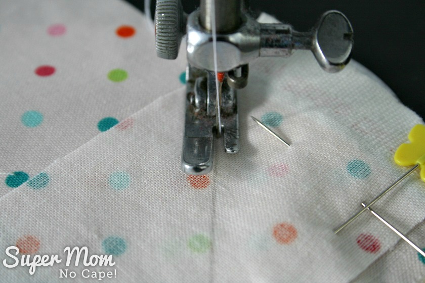 Close up photo of the needle going into the fabric on the right hand side of the drawn line