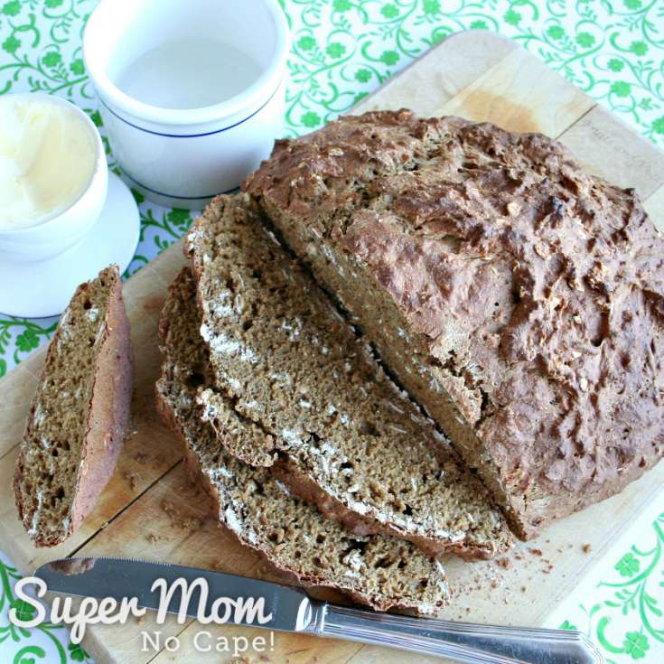 Fresh baked Irish Soda Bread with a Rye Twist on a cutting board with butter bell beside it