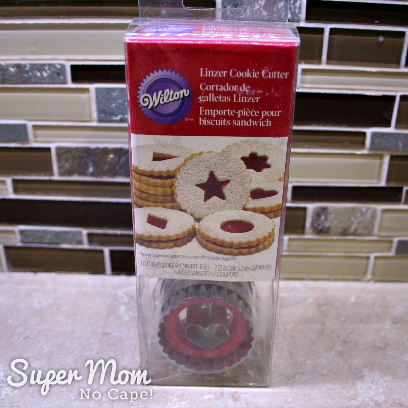 Photo of a Wilton Linzer Cookie Cutter Kit sitting on a kitchen counter with the brown tiles backsplash in the background