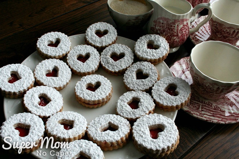 Plate of Snow Storm Linzer Cookies beside tea cup and creamer and sugar bowl