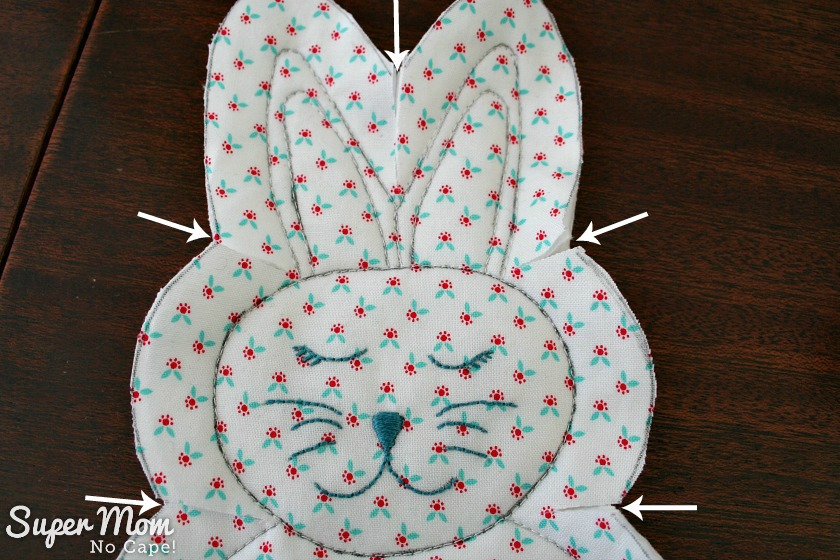 Close up of bunny head with white arrows showing where to clip