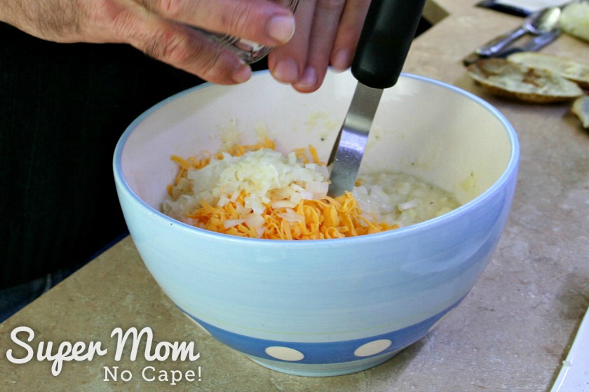 Adding chopped onions and grated cheese to the bowl with the mixture for Twice Baked Potatoes