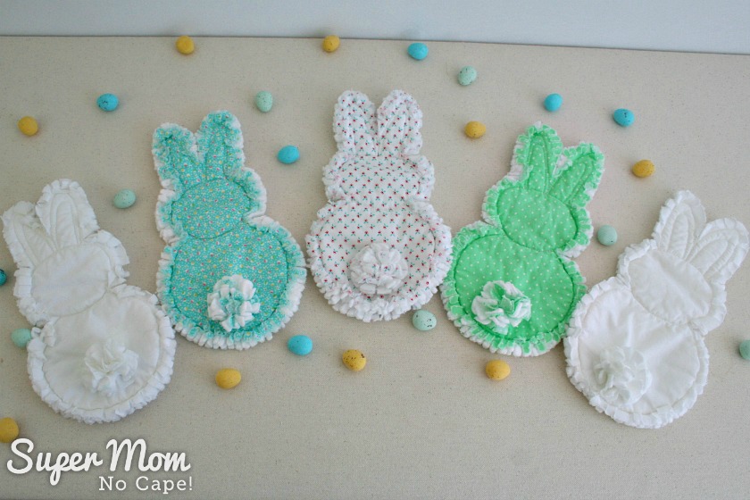 Backs of five rag quilt bunnies with candy eggs