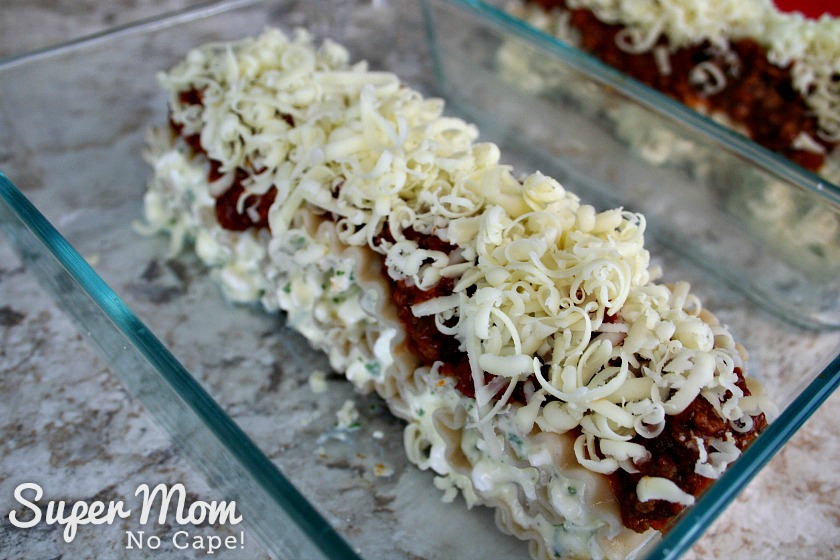 Lasagna roll ups topped with meat sauce and grated mozzarella cheese