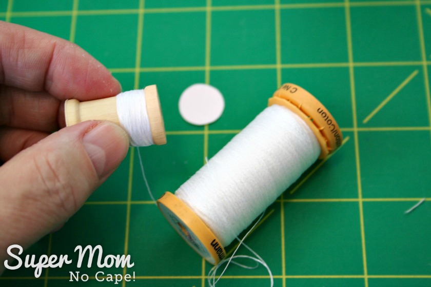  Wrapping white thread around small wooden spool