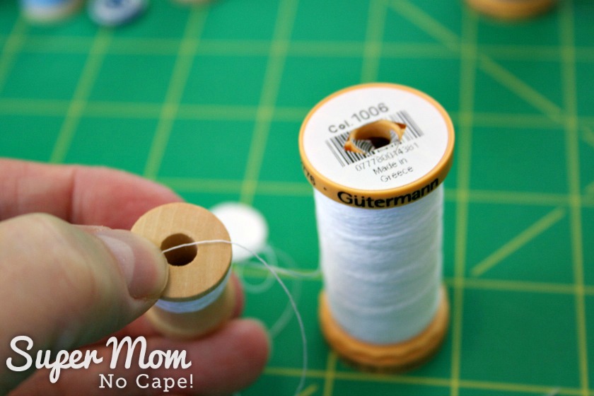 Lay end of thread over the top of the miniature wooden spool