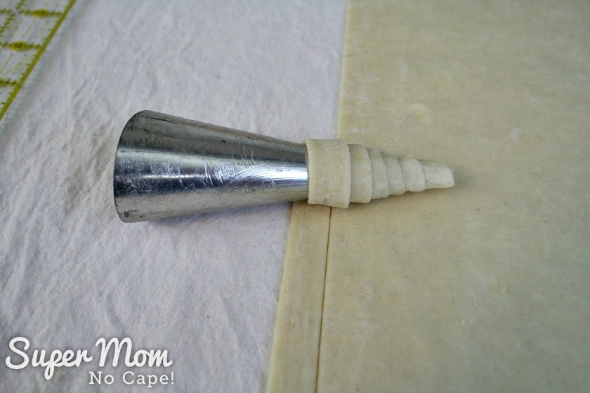Continue rolling the strip of puff pastry on the metal pastry horn