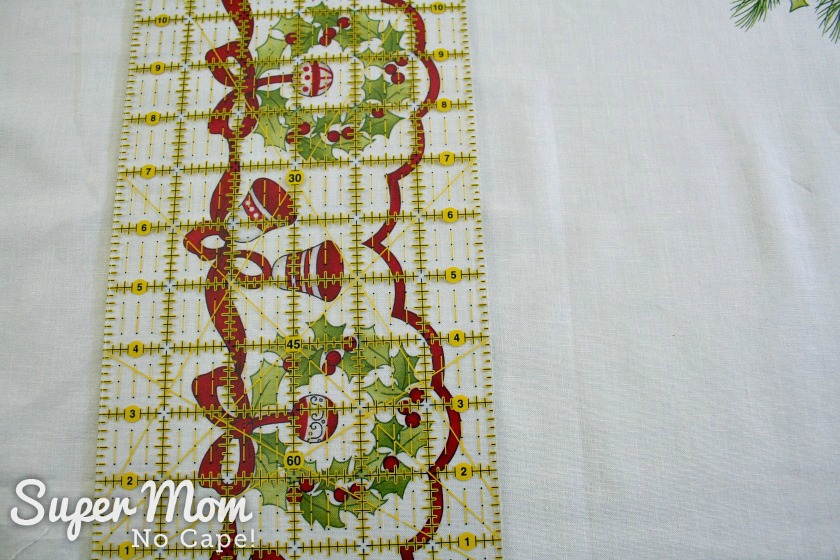 Measuring to cut the border off the Ring in the Holly Days fabric panel