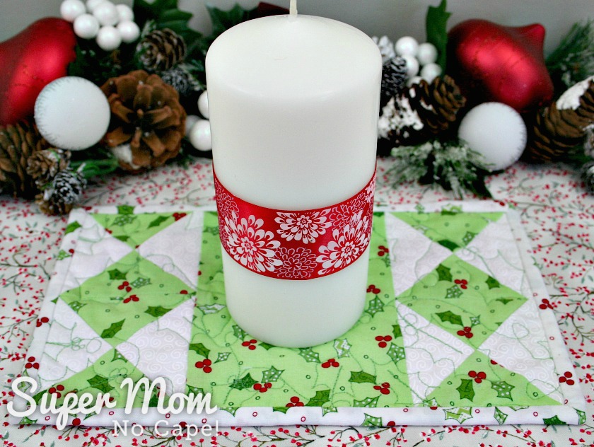 Candle with ribbon sitting on hourglass candle mat