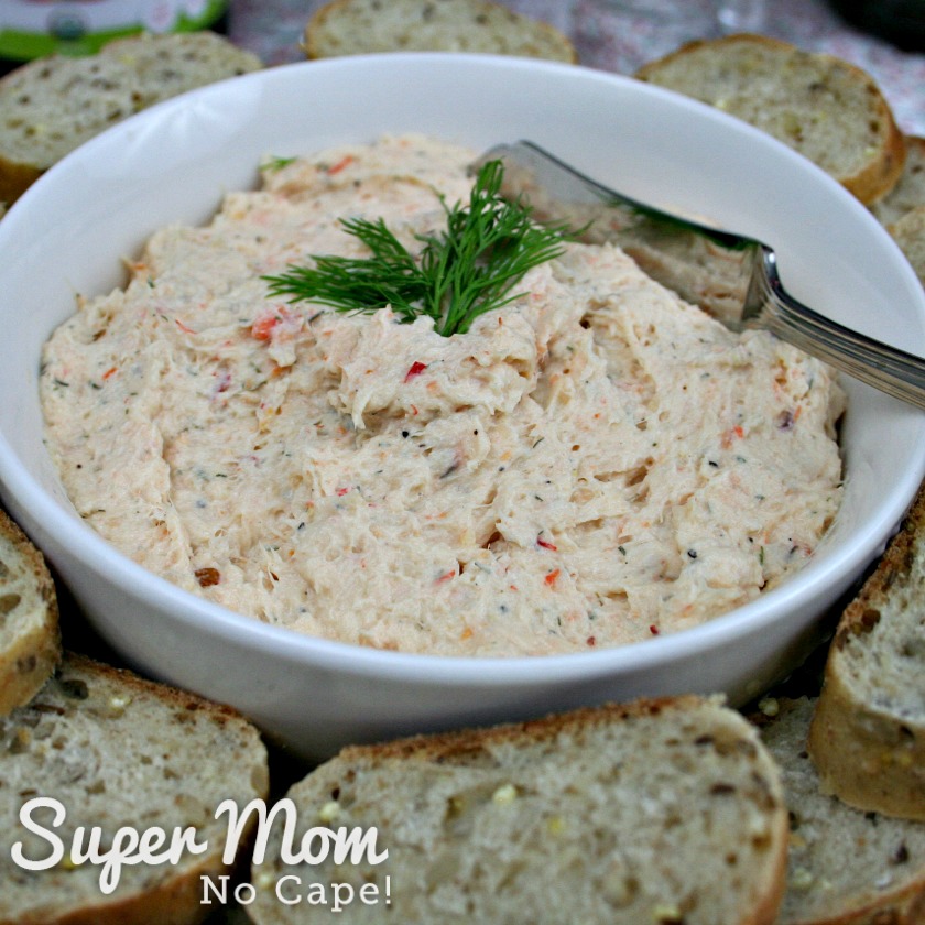 Close up photo of Sweet Chili Shrimp Dip in a white bowl with serving knife surrounded by slice bread