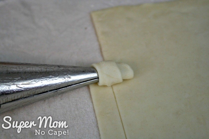 Begin rolling the strip of puff pastry onto the metal pastry horn