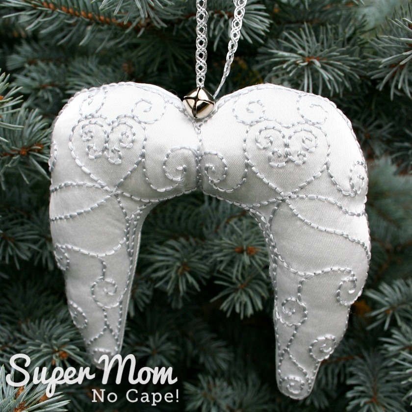 Embroidered Angel Wings Ornament hanging on an evergreen tree