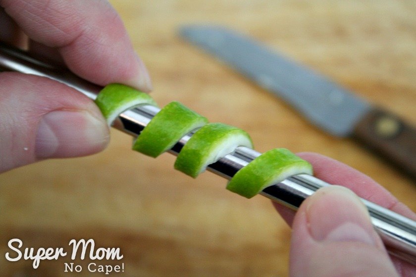 Curling the slice of lime rind around a metal straw