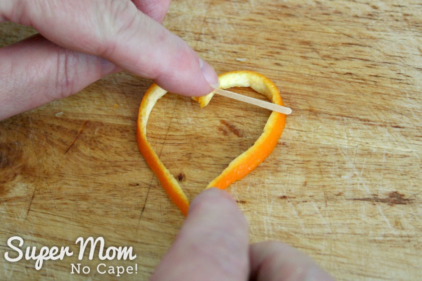 Squeezing orange rind to make a point to form a heart garnish