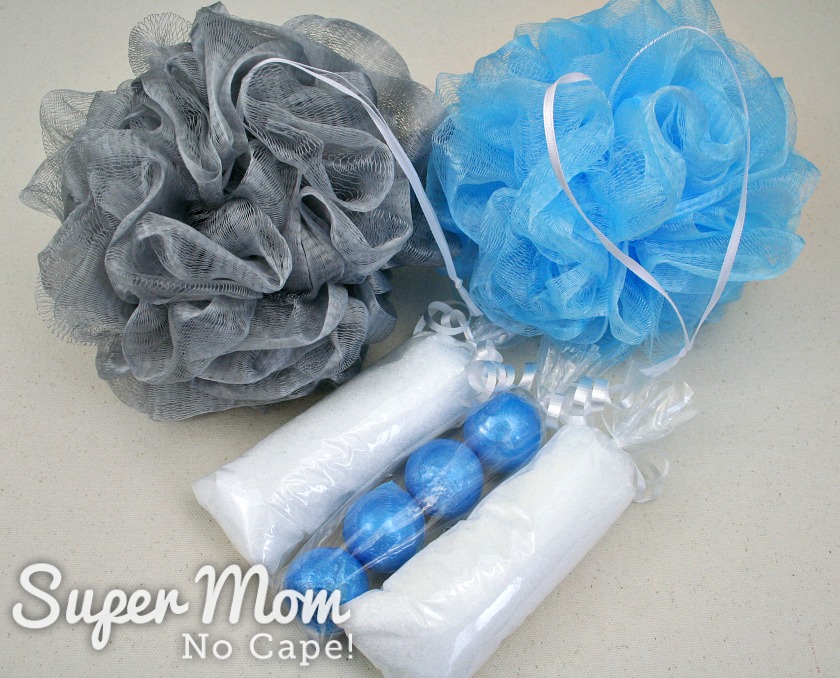 One grey and one blue shower puff after being repaired along with packages of bath balls and bath salt s