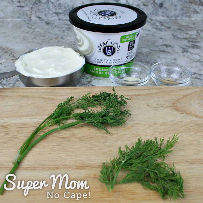 Sprigs of dill for Dilly Greek Yogurt Dip on a cutting board with other ingredients in the background