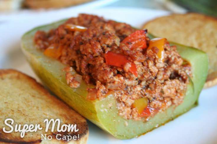 Half of a Sausage Stuffed Zucchini Pizza Boat with toasted bread on a white plate