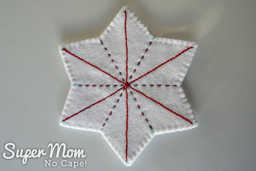 White felt star with red embroidery lines and white blanket stitch.