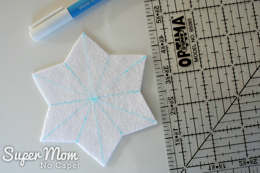 White felt star with blue lines drawn on, ruler and top part of water soluble pen.