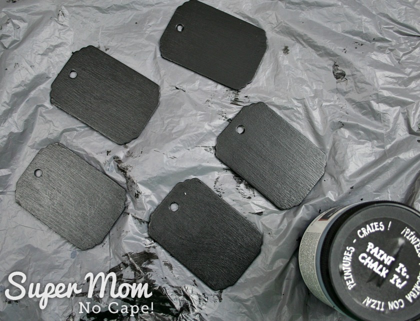 Five wood tags painted black with a small container of black chalkboard paint