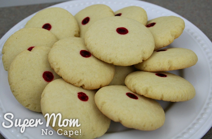 Almond cookies with red dots arranged in a circle on a white plate