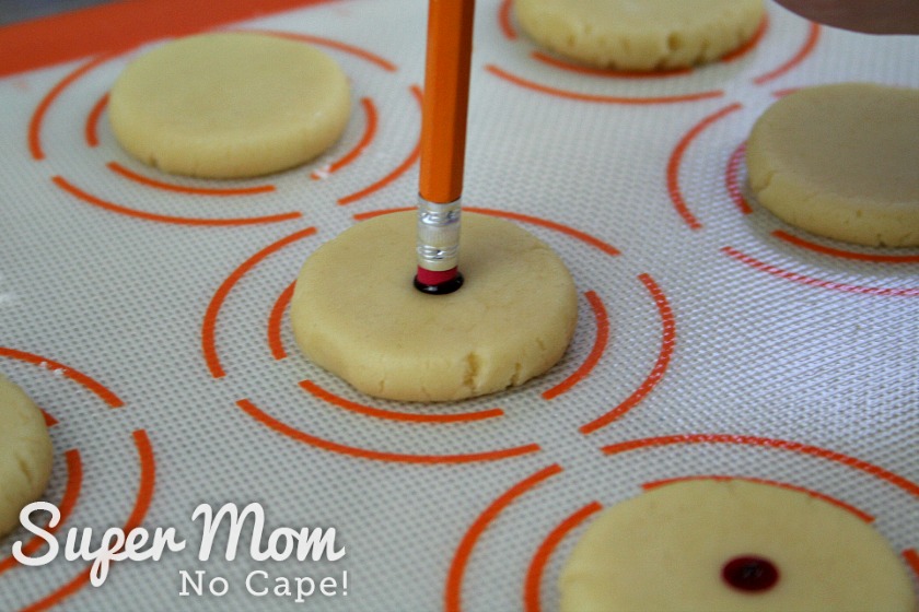 Making red dots on the almond cookies with a pencil eraser dipped in red food coloring