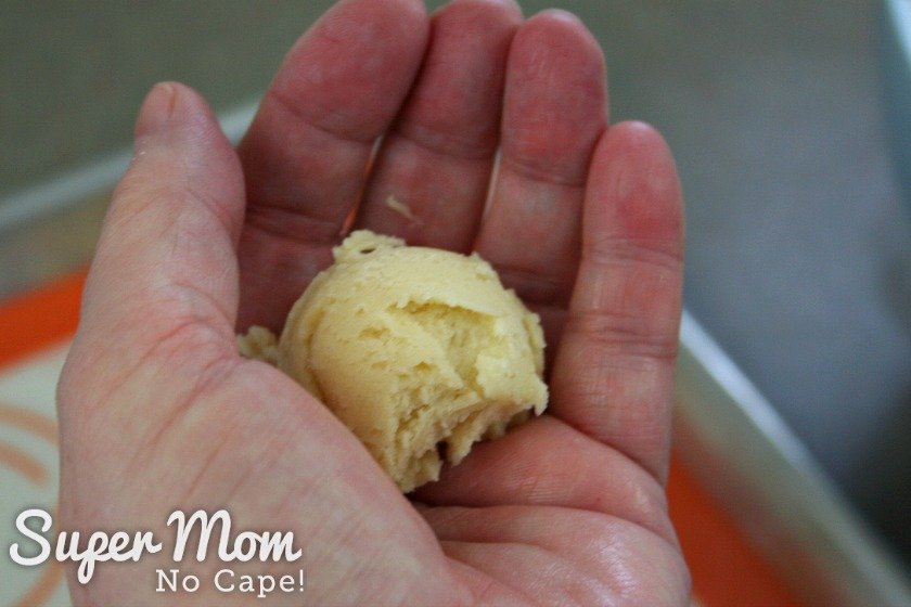 Rounded scoop of almond cookie dough in the palm of a hand