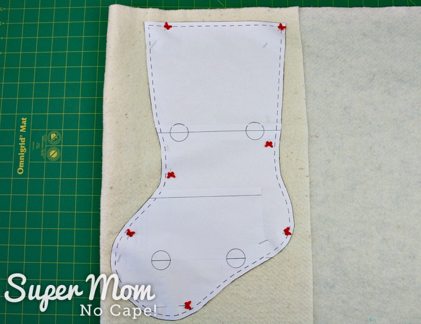 Paper stocking pattern pinned to double layer of batting laid out on a cutting mat.