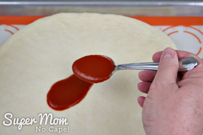 Spooning the enchilada sauce onto the pizza dough