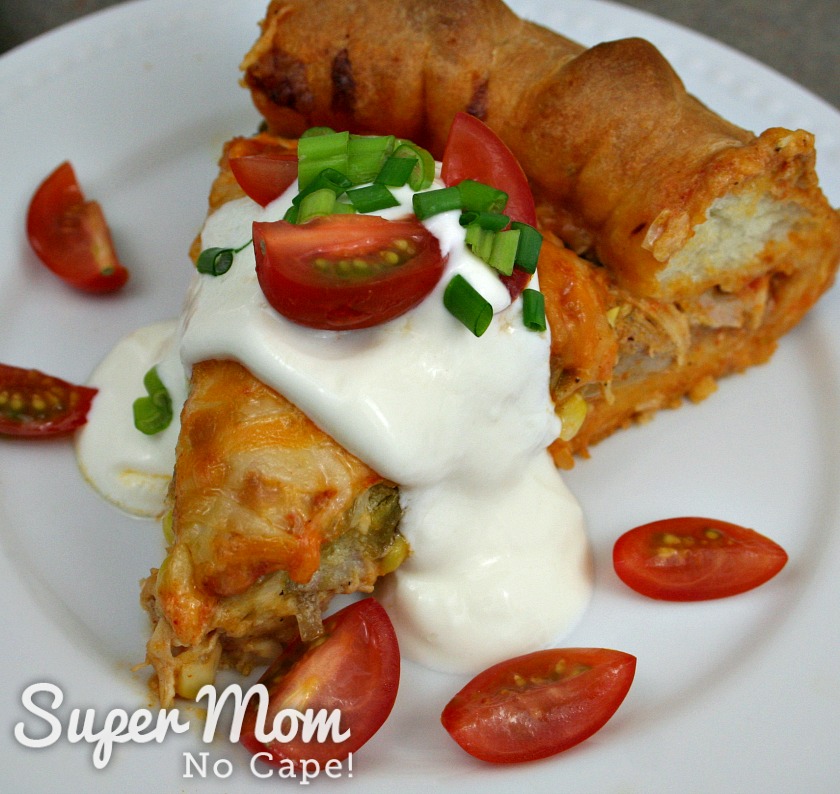 A picture of a slice of the turkey enchilada tart, topped with sour cream, green onion and chopped cherry tomatoes